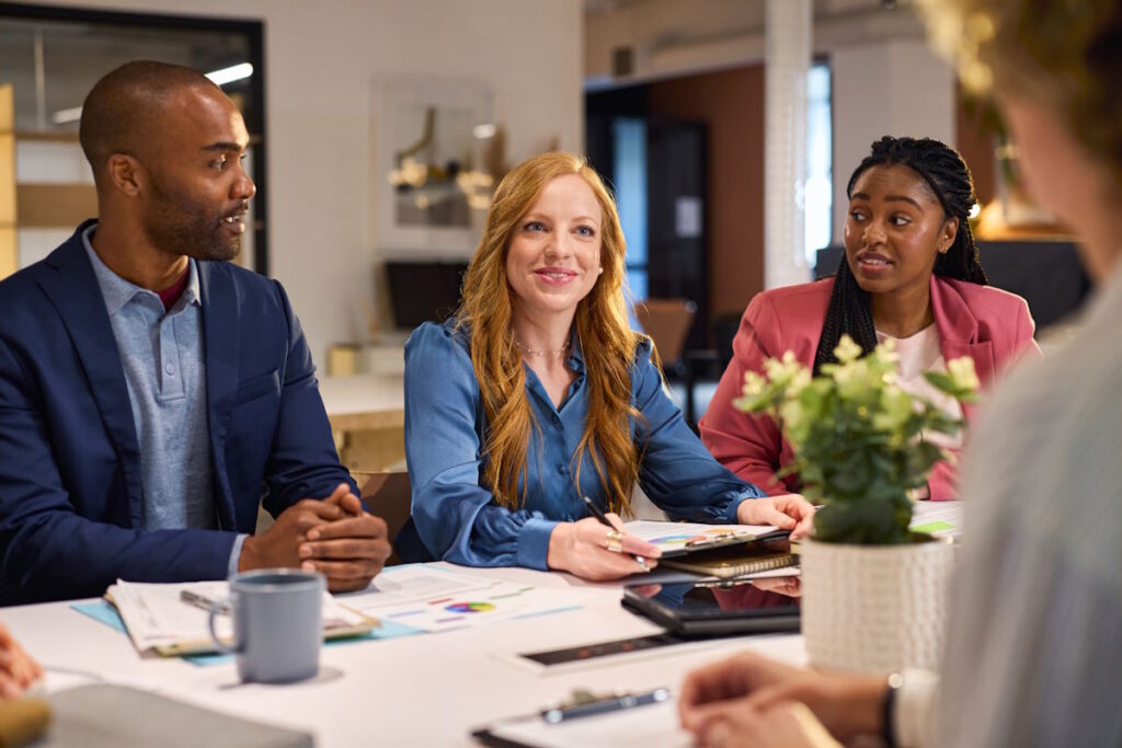 Group of mixed race business people discussing work in conference room. Beautiful businesswoman guiding employees in meeting. Group of african american businessman and businesswomen working together while brainstorming and sharing new ideas and strategy.
